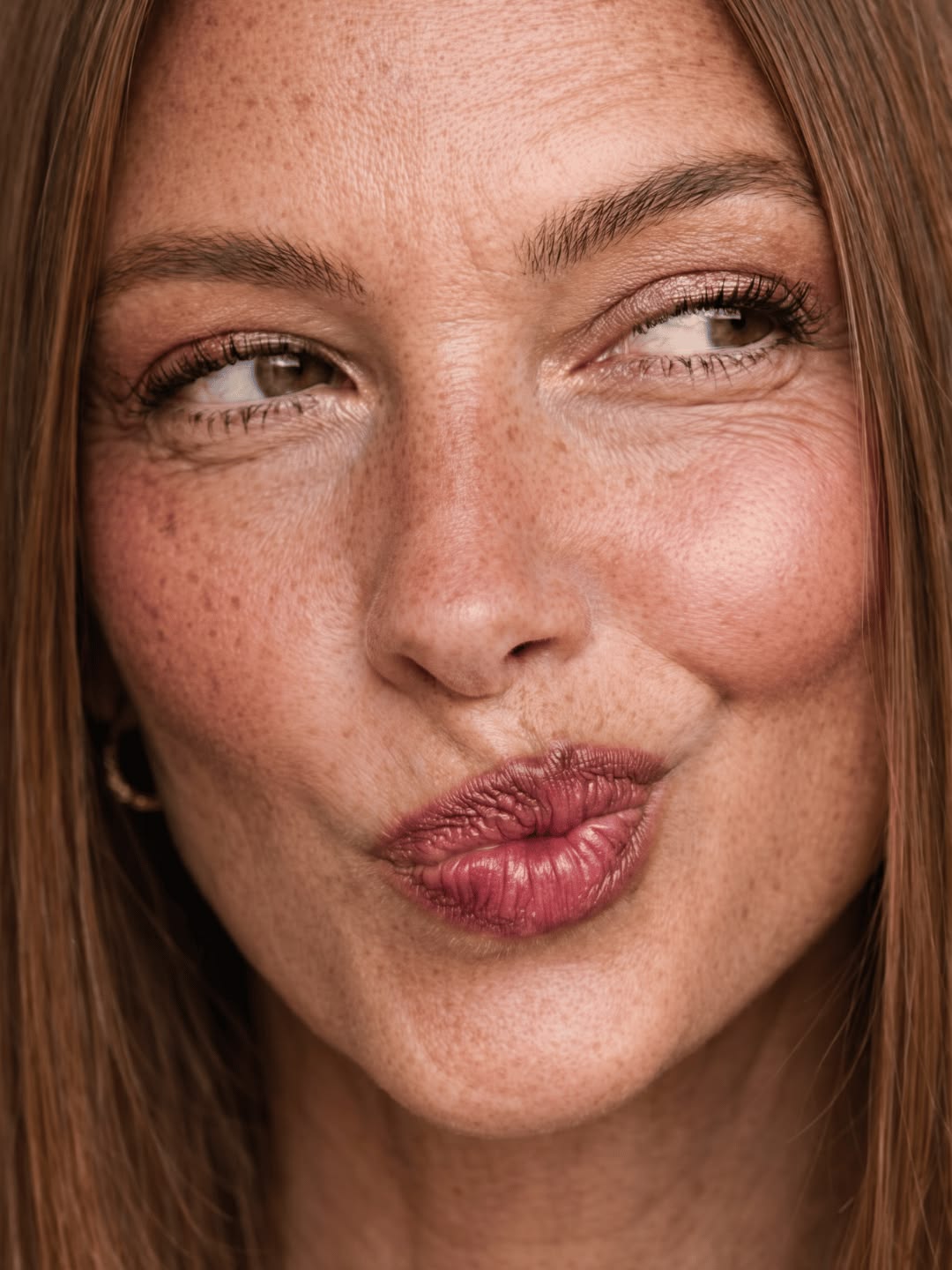 Gros plan d'un visage à taches de rousseur, lèvres en bisou