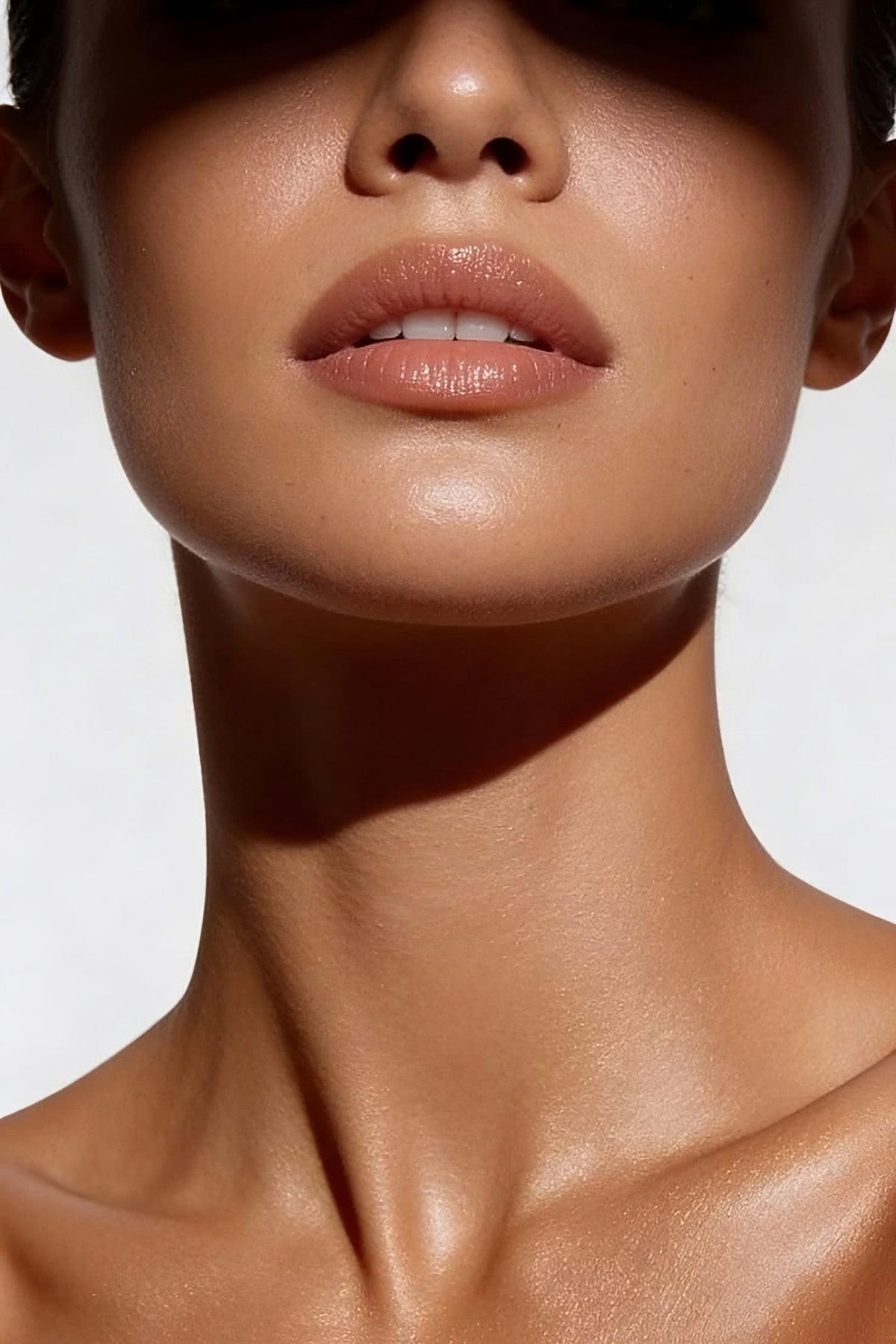 Gros plan sur le bas du visage et le cou d'une femme, peau lumineuse dans une lumière naturelle