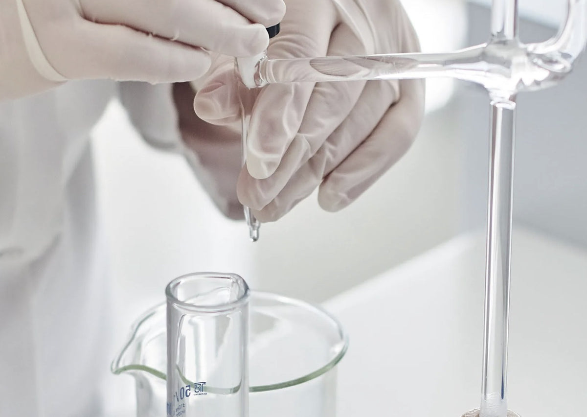 Formulation en laboratoire : une pipette dépose une goutte au-dessus d'un bécher gradué